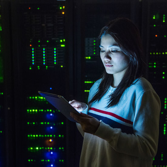 Young woman working on digital tablet in server room