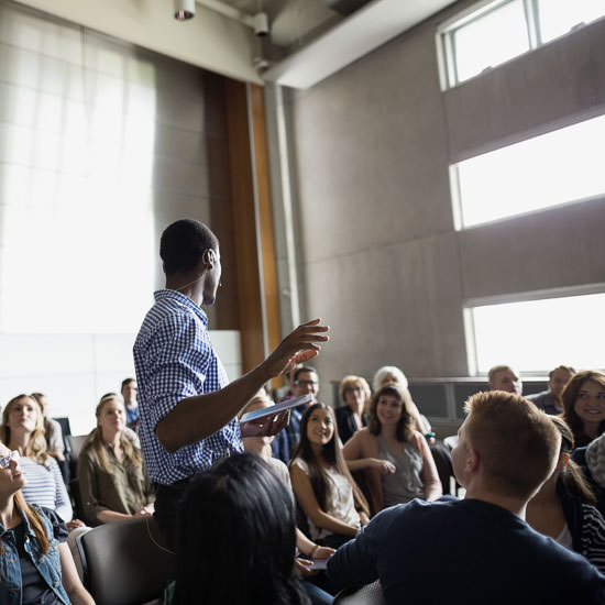 Professor giving lecture among auditorium audience