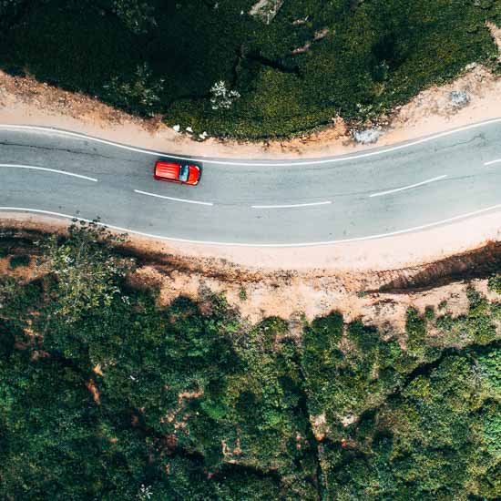 Aerial view on  red car on the road near green tea plantation in mountains in Sri Lanka