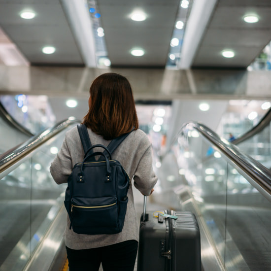 Young woman holding suitcase or baggage with backpack in the international airport.