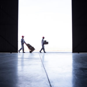 Two couriers working together to deliver parcels and boxes outside a warehouse door