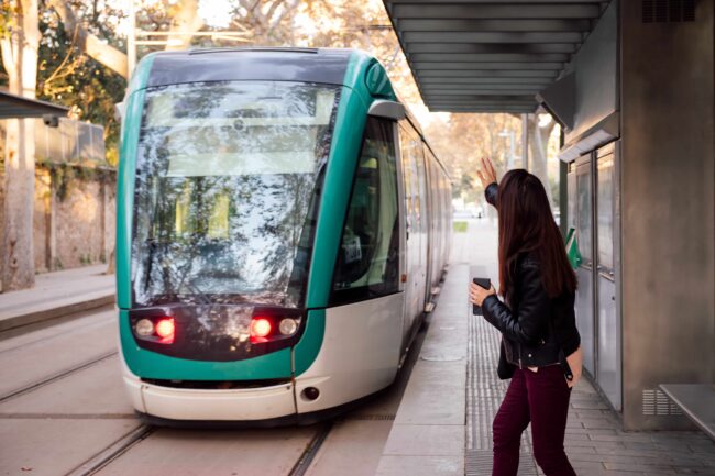 woman raising her hand to call for the streetcar mobilité durable, mobilité, train, tramway, transport
